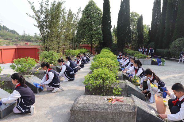 同学们为烈士擦拭墓碑。